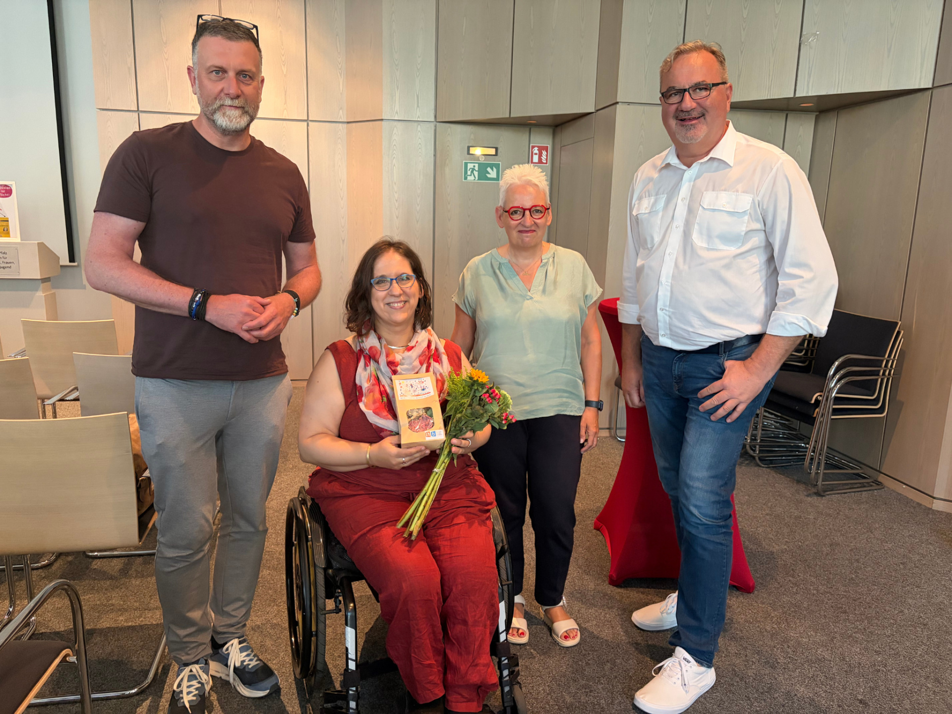 Eine Gruppe von Personen stehen im Halbkreis. In der Mitte eine Frau im Rollstuhl. 
&copy; LAG WfbM RLP