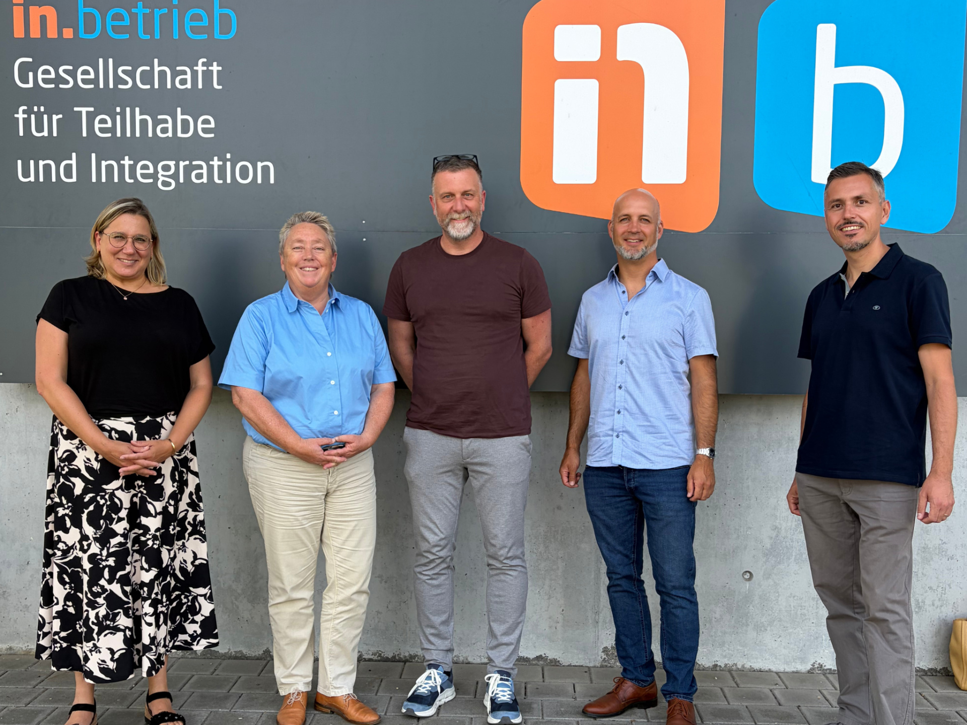 Eine Gruppe von Personen steht vor dem Eingangsschild einer WfbM 
&copy; LAG WfbM RLP